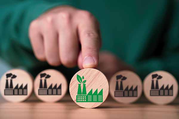 Transparent Service Benefits of Product Destruction Hand pointing at circular wooden block with icon of a energy recovery facility with leaves emerging from the smoke stack. There are 4 additional blocks lined up in the back with black icons of factories producing smoke
